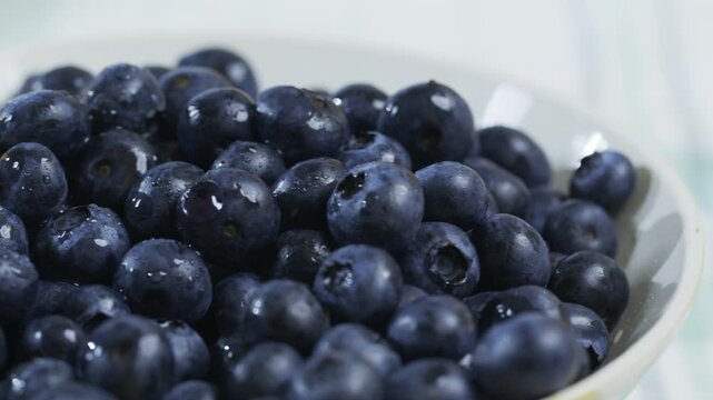 Panning closeup shot across fresh blueberries in bowl