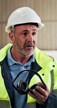 Carpenter, talking and man with ear muffs, conversation and safety briefing for team and compliance. Woodworking, supervisor and mature person with PPE, hearing protection and instructions in factory