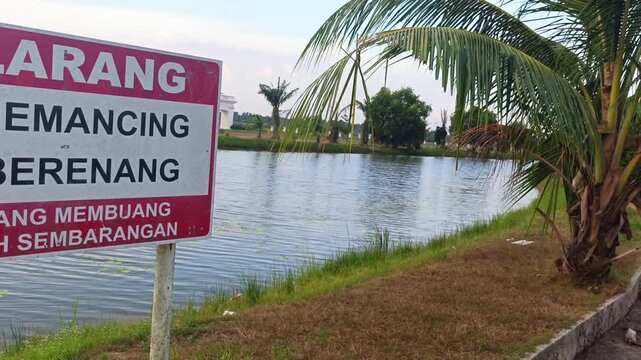 Warning sign prohibiting fishing and swimming near lake