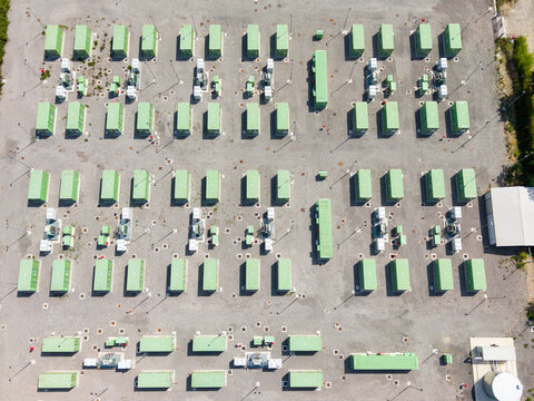 Aerial view of a modern battery energy storage system with rows of green containers and power equipment on a gravel site in Tavazzano con Villavesco, Lombardy, Italy.
