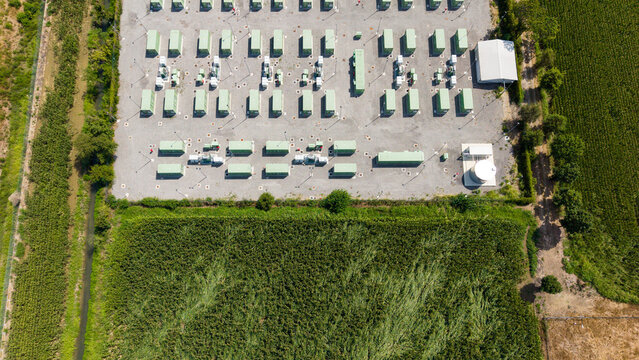 Aerial view of a modern Battery Energy Storage System with rows of green containerized units, power transformers, and equipment in Tavazzano con Villavesco, Lombardy, Italy.