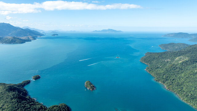 Aerial view of Lagoa Azul, also known as Blue Lagoon, featuring turquoise waters, lush green islands, and boat wakes under a clear blue sky in Angra dos Reis, Rio de Janeiro, Brazil.