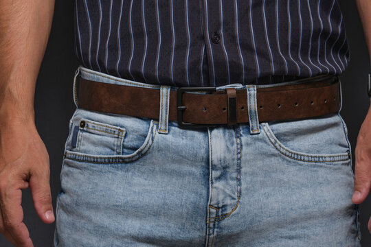 Front view man dressed in light blue denim jeans with stylish brown leather belt.