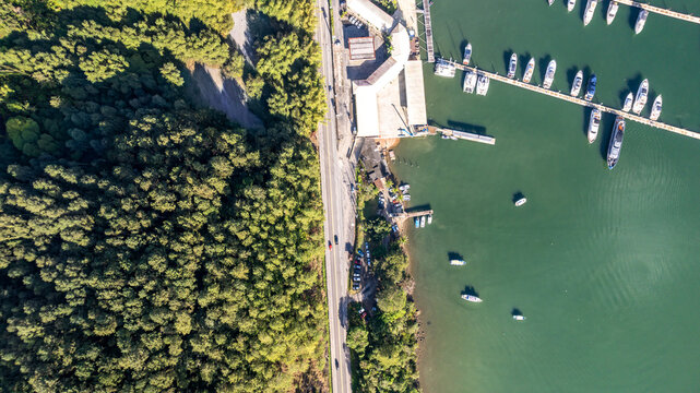 Aerial view of the marina with numerous boats docked along the pier, bordered by a lush forest and a coastal road in Angra dos Reis, State of Rio de Janeiro, Brazil.