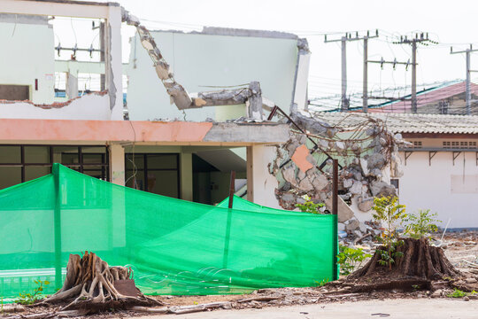 Old house being demolished in the foreground while modern apartment buildings rise in the background, symbolizing progress and redevelopment