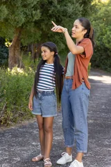 African American mother with child standing on paved path pointing right, wearing watch and shoes © wavebreak3