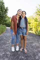 Mother and daughter standing on paved park path, wearing rust shirt and striped t-shirt © wavebreak3