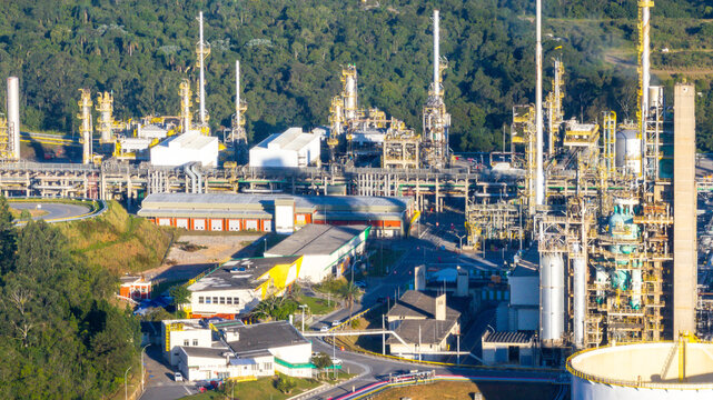 Aerial view of the petrochemical complex featuring industrial towers, pipelines, and storage tanks surrounded by lush forest in Santo Andre, State of Sao Paulo, Brazil.