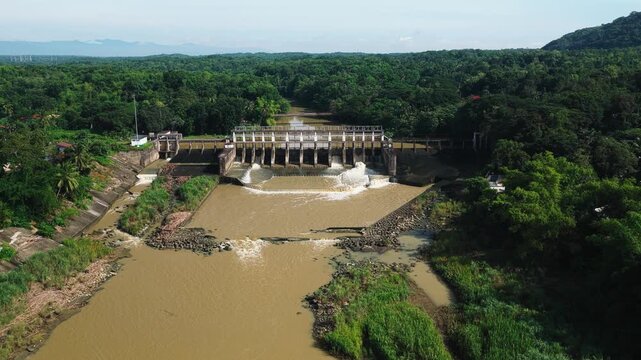Aerial view of Jalaur Dam surrounded by lush greenery and flowing river water in Dingle, Western Visayas, Philippines.