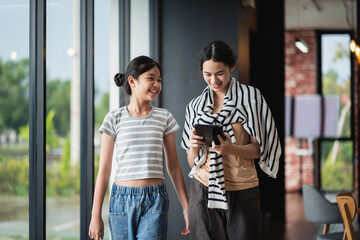 Digital Education with two Asian female students walking together and viewing a tablet while...