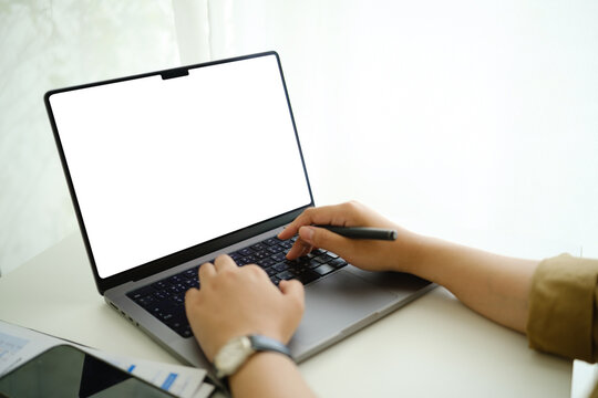 Young businesswoman working from home with a blank laptop display, ideal for website, application, or online service mockups.