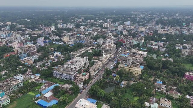Aerial view of Al Jamiatul Ahlia Darul Uloom Moinul Islam-Hathazari surrounded by dense urban buildings, lush green trees, and roads in Hathazari, Chittagong Division, Bangladesh.