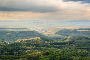 Naklejka premium Layers of green mountains and hills in the haze during sunset. Panoramic View of Green hills and Meadow.