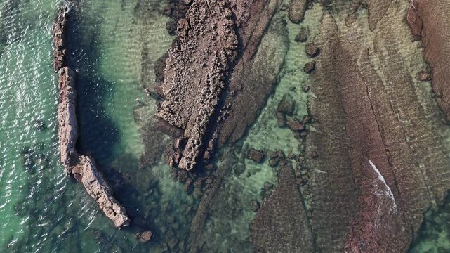 Aerial view of Praia das Avencas with rocky formations and clear turquoise water along the coastline in Cascais, Lisboa, Portugal.