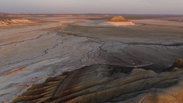 Aerial view of the unique geological formation of Gora Bokty surrounded by arid desert terrain during golden hour in Karakiya District, Mangystau Region, Kazakhstan.