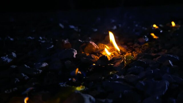 Dangerous yellow plastic waste burning and melting on the ground at night, producing bright orange flames and toxic smoke, causing harmful environmental pollution from hazardous materials