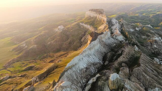 Aerial view of the dramatic limestone formations of Airakty mountains during golden hour in the vast landscape of Shetpe, Mangystau Region, Kazakhstan.