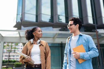 Latino male and African female students walking on campus outdoors.  © Kawee