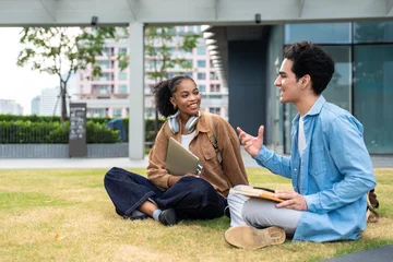 Latino male and African American female student sitting outdoors on campus.  © Kawee