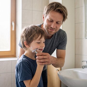 Vater bringt Sohn im Badezimmer das Rasieren mit Rasierschaum bei