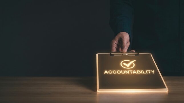 Professional hand holding glowing clipboard displaying accountability concept with checkmark symbol in dark office setting