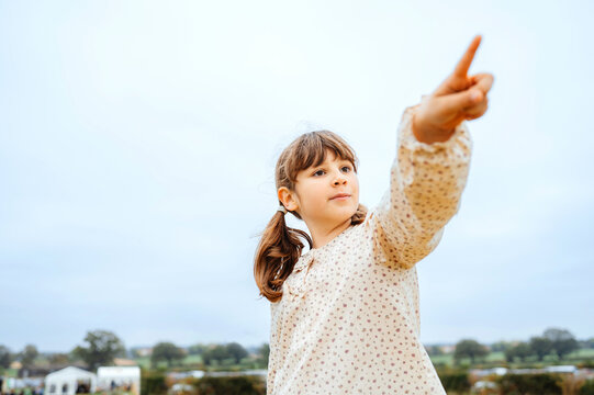 Girl pointing into the distance under a cloudy sky