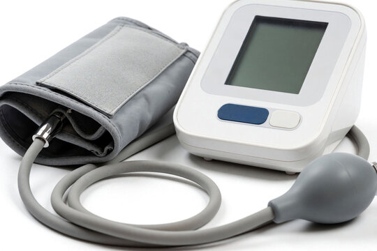 Digital blood pressure monitor device sits on white surface. Electronic health equipment checks heart pulse rate at home clinic. Modern medical tool measures human arterial tension during checkup