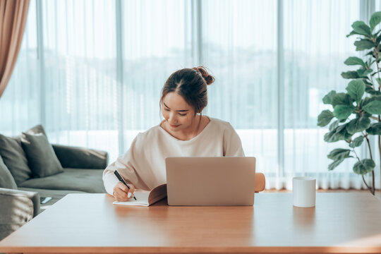 Attractive smiling young asian business woman work at home office, Asian woman working on laptop computer in living room