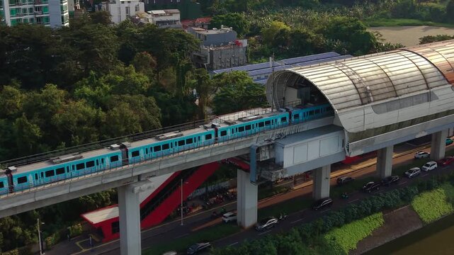 Aerial view of a modern MRT Jakarta train traveling on an elevated track above a road with cars, surrounded by lush green trees in Jakarta, Jakarta, Indonesia.