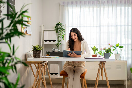 Hispanic woman quietly reading a book while sitting on working table.