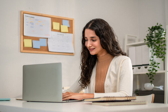 Hispanic young businesswoman typing on laptop while working from home. 