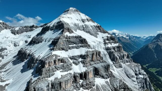 Majestic snow-covered mountain peak with steep cliffs against a bright blue sky on a sunny day