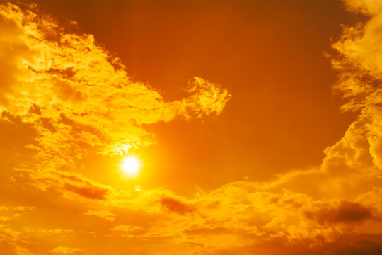Orange sky with blazing sun and dramatic clouds, symbolizing extreme heat, global boiling, climate change, heatwave, and rising temperatures.