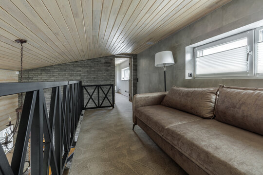 Mezzanine Floor Interior with Sofa, Metal Railing, and Sloped Ceiling