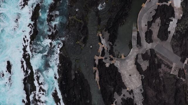 Aerial view of the volcanic rock formations and turquoise ocean waves at Piscinas Naturais Biscoitos in Biscoitos, Azores, Portugal.