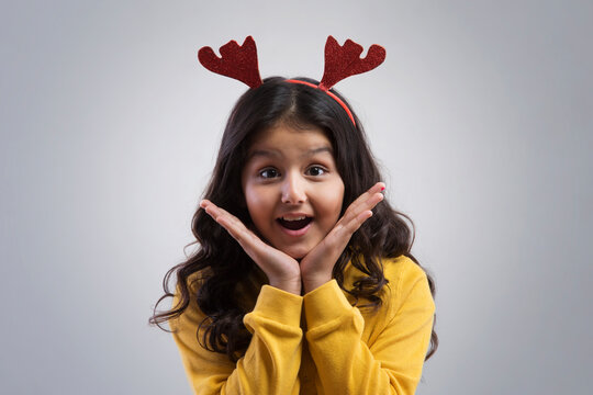 Portrait of a happy young girl wearing a reindeer antlers headband. (Christmas) 