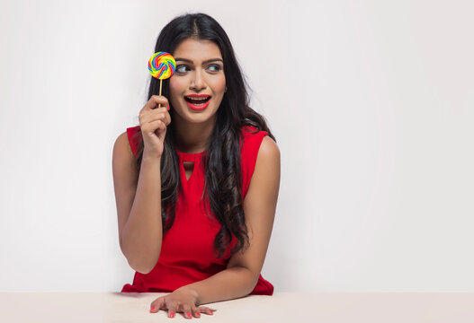 Portrait of a young woman holding a lollipop in hand.