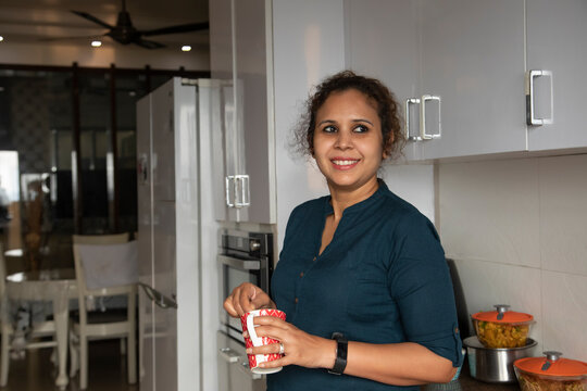 Young woman standing in the kitchen and beating coffee in the cup. 