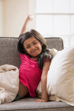 Young girl stretching after taking a nap on the sofa at home. (Children)