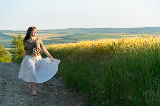 Happy Young Woman Dancing in White Skirt on Summer Path
