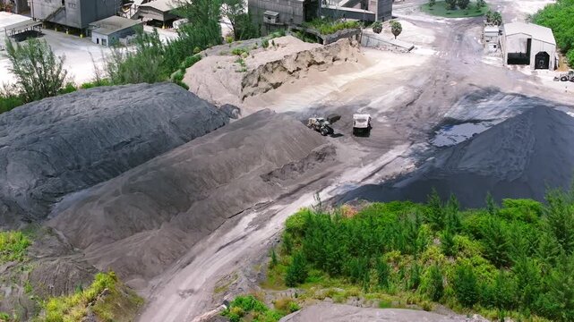 Aerial view of cement plant with heavy machinery and large piles of aggregate at an industrial site in Miami, Florida, United States.