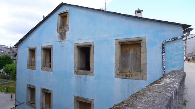 Casa antigua abandonada con fachada azul envejecida y ventanas de madera, mostrando el deterioro y el paso del tiempo en su arquitectura tradicional Gallega.