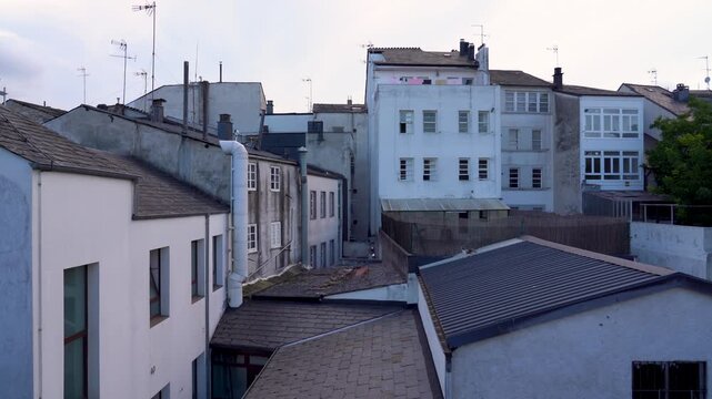 Detalle de un gato sobre los tejados de varias casas antiguas, observando desde lo alto el entorno de un barrio hist&oacute;rico.