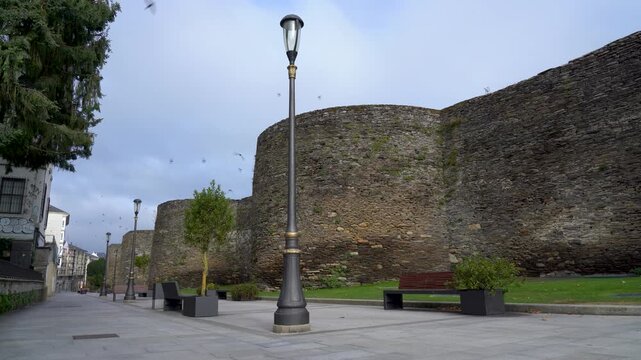 Vista de la muralla romana de Lugo desde su base, destacando la inmensidad, altura y solidez de esta monumental fortificaci&oacute;n hist&oacute;rica.