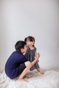 An Asian boy is holding a little girl and playing indoors.