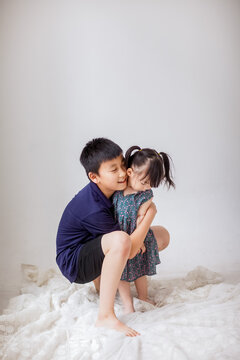 An Asian boy is holding a little girl and playing indoors.