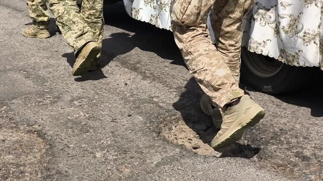 Low angle view of soldiers in military camouflage standing next to a vehicle