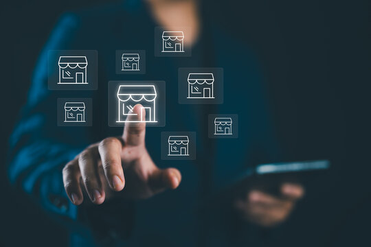 Businessman hand pointing to virtual shopping store which connection line with others small shopping stores , expand and development franchise concept.