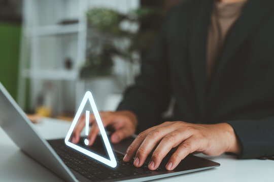 Businessman using computer laptop with triangle caution warning sign for notification error and maintenance concept.