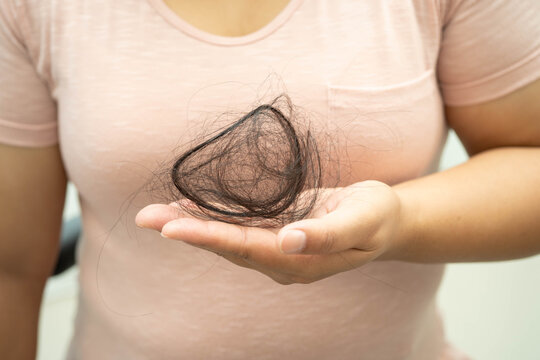 Asian woman have problem with long hair loss attach in her hand.